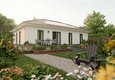 Effizienter Bungalow 110 mit Photovoltaik-Anlage auf dem Walmdach, moderner Terrasse und grünem Garten